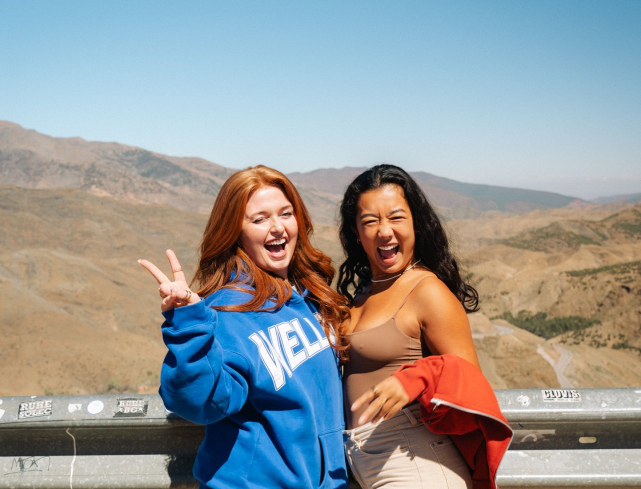 Two female travellers pose overlooking the Atlas Mountains during a travel day on their Morocco group tour