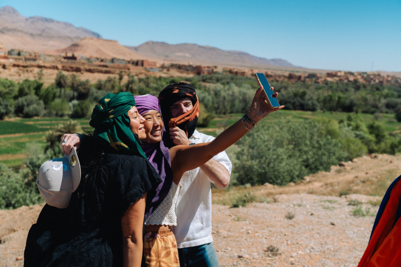 A trio of young travellers take a selfie with the amazing backdrop of the Moroccan countryside on day 3 of their group tour