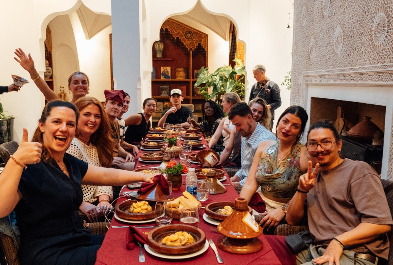 A group of friends on a group tour with TruTravels pose with the meals they have just cooked during a local cooking class in Marrakech